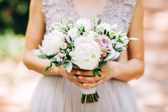 tender bride holding a wedding bouquet. bride on nature with a bouquet of peonies.