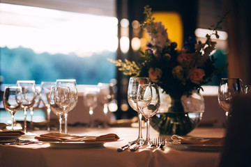 round table with a white tablecloth. the table is decorated with a vase of flowers. wine glass and champagne glass.