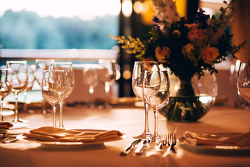 round table with a white tablecloth. the table is decorated with a vase of flowers. wine glass and...