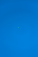 View of a paraglider hovering in the air, blue sky as background