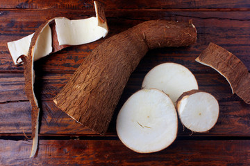 fresh cassava and peels and slices on rustic wooden table