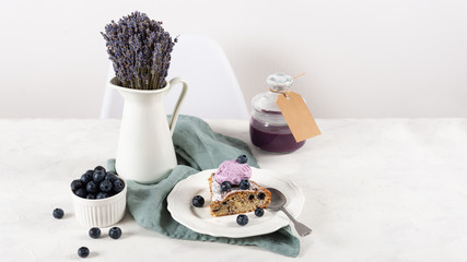 cut of blueberry homemade cake with ice cream ball, blueberry jam in jar and lavender bouquet on white background. Backery concept, copy space