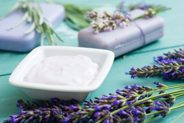 lavender soaps and cosmetic cream, flowers on blue wooden table