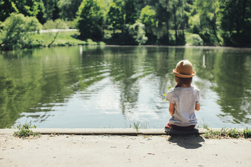 Girl sitting by the lake in the park back view