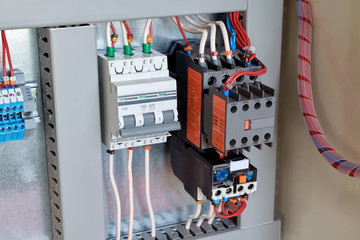 Circuit breaker, contactor or starter with additional contacts and thermal relay in electrical Cabinet. Electric control Cabinet for pumps or motors. The wires are connected to electrical equipment.