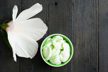 cosmetic cream and white mallow flower on black wood table