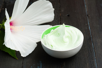 cosmetic cream and white mallow flower on black wood table