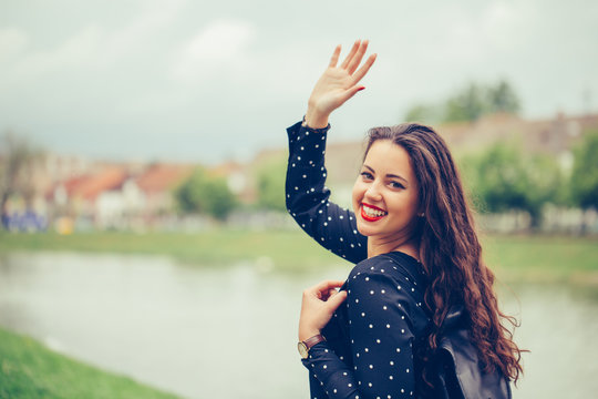 Portrait of a beautiful  woman walking outdoors, waving her hand