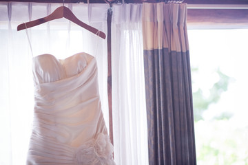 Wedding Dress hanging on Curtain rail near window in room