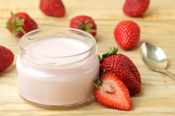 delicious strawberry yogurt in a jar and fresh ripe strawberries on a natural wooden table