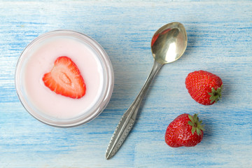 delicious strawberry yogurt in a jar and fresh ripe strawberries on a light blue wooden table. top view