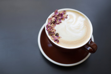 Cup of coffee on black rustic background with beautiful latte. Coffee foam with flowers. Cappuccino. 