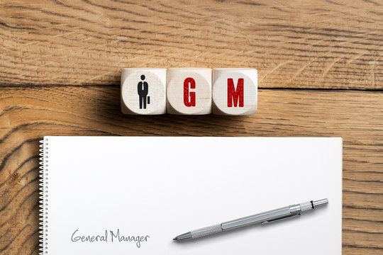 W&uuml;rfel mit Abk&uuml;rzung GM und Erkl&auml;rung als "General Manager" auf Papier