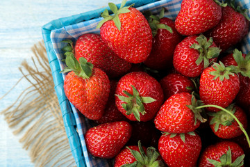 Ripe, delicious strawberries. Red strawberry in a wicker basket on a light blue wooden table. top view