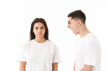 Angry young couple standing isolated over white background