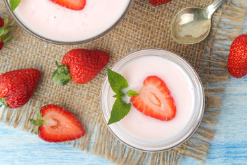 delicious strawberry yogurt in a jar and fresh ripe strawberries on a light blue wooden table. top view
