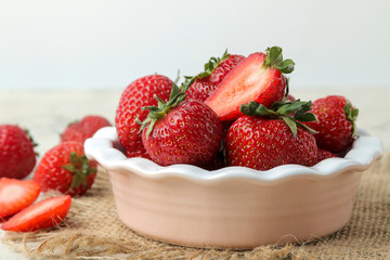 Ripe, delicious strawberries. Red strawberry in a ceramic bowl on a light concrete table. close-up