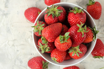Ripe, delicious strawberries. Red strawberry in a ceramic bowl on a light concrete table. top view
