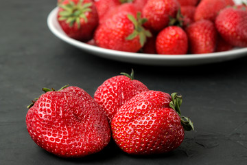 Ripe, delicious strawberries. Red strawberry berry closeup on a black concrete table.
