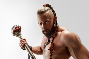 Serious long hair and muscular male model in leather viking's costume with the big mace cosplaying isolated on white studio background. Half-length portrait. Fantasy warrior, antique battle concept.