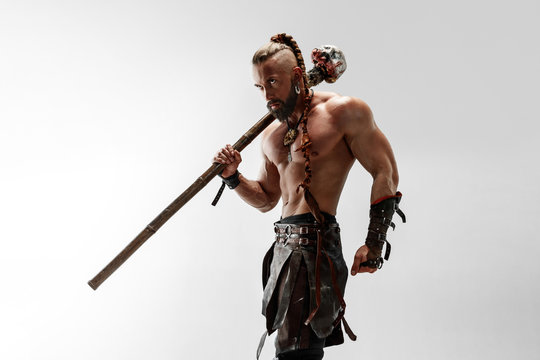 Serious long hair and muscular male model in leather viking's costume with the big mace cosplaying isolated on white studio background. Half-length portrait. Fantasy warrior, antique battle concept.