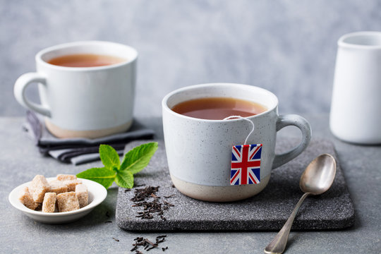 Tea in mugs with British flag tea bag label. Grey background. Close up.