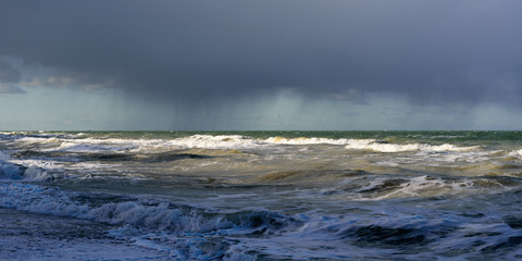 Waves on the Baltic Sea against dark blue dramatic thunderclouds