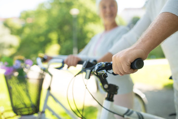 Obraz premium old age, people and lifestyle concept - close up of senior couple with bicycles at park in summer