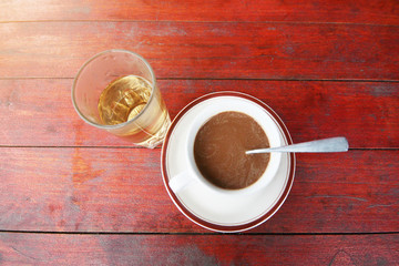 A cup of hot coffe and glass of hot tea on wood table.