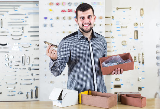 male seller sorting boxes with door handles in houseware shop