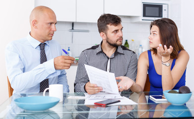 Obraz premium Unhappy young couple signing financial agreement with social worker