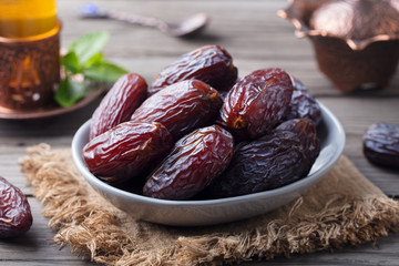 Fresh Medjool Dates in a bowl with tea. Ramadan kareem. Grey wooden background.