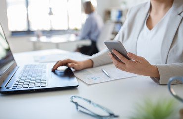 business, technology and people concept - businesswoman with smartphone and laptop computer at office