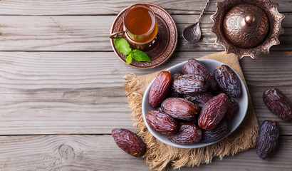 Fresh Medjool Dates in a bowl with tea. Ramadan kareem. Wooden background. Top view. Copy space.