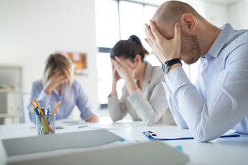 business, failure and people concept - stressed colleagues team with papers at office meeting