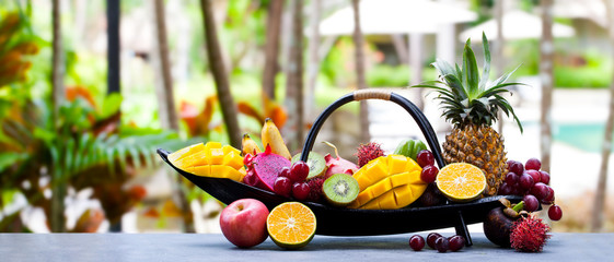 Tropical fruits assortment in wooden boat. Outdoor tropical background. Copy space.