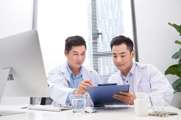 Obraz premium Two doctors holding and talking about patient on office