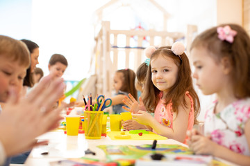 kindergarten children doing arts and crafts with teacher in day care centre - 268836577