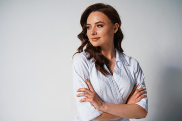 Portrait of beautiful young female doctor in white medical jacket isolated on white background. Brunette woman cosmetologist with cross hands. Copy space. Medical concept. Healthcare