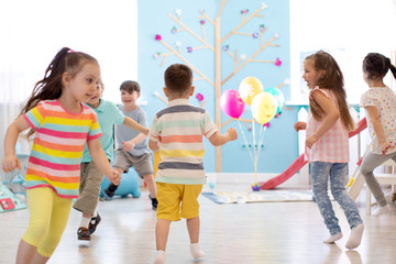 childhood, leisure and people concept - group of happy children playing tag game and running indoors