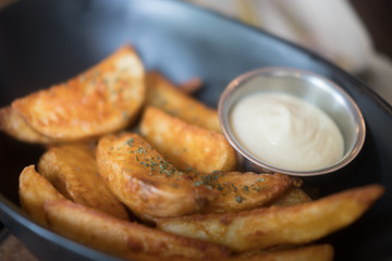 Potato wedges in small bowl with sour cream