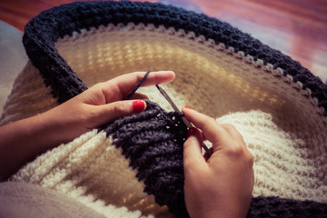 Girl making a crochet puff with white and gray wool and nails painted red