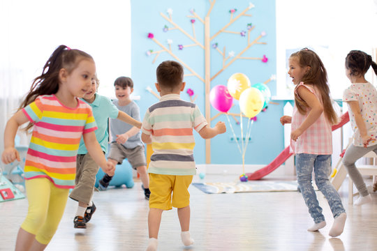 childhood, leisure and people concept - group of happy children playing tag game and running indoors