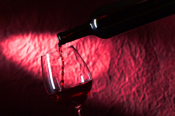 Bottle and glass of red wine on a dark  background