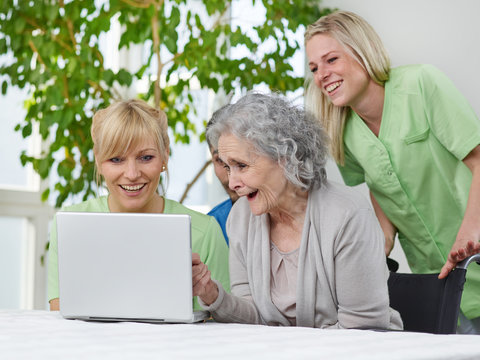 Seniorin mit Pflegern am Laptop