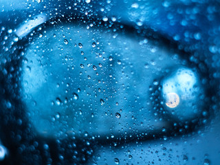 Abstract water drop let on window with car side mirror out of focus