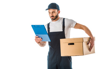 attentive handsome delivery man holding cardboard box and looking at clipboard isolated on white