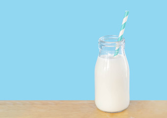 Bottle of fresh milk with straw on light blue background with copy space, food healthy concept