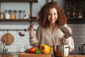 Photo of adorable caucasian woman holding cooking ladle spoon while eating soup at home