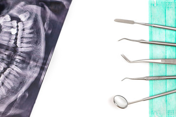 Dentist tools on mask and x-ray photo.